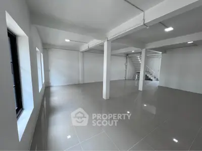 Spacious open-plan interior with sleek tiled flooring and modern lighting, perfect for versatile living or office space.