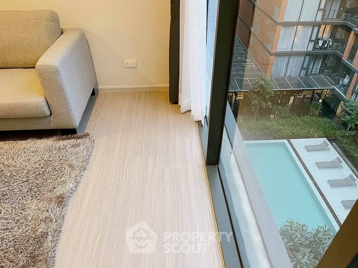 Modern living room with large window overlooking pool and garden in luxury apartment.