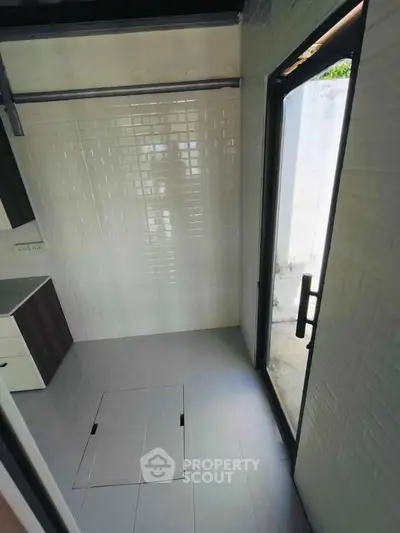 Compact kitchen space with modern white tiles and large glass door