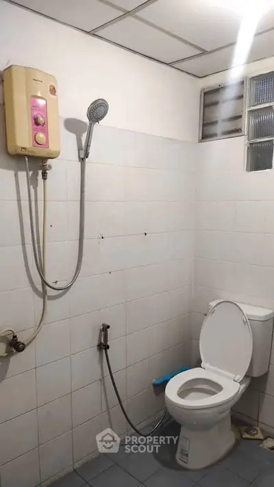 Simple bathroom with shower and toilet in a tiled setting