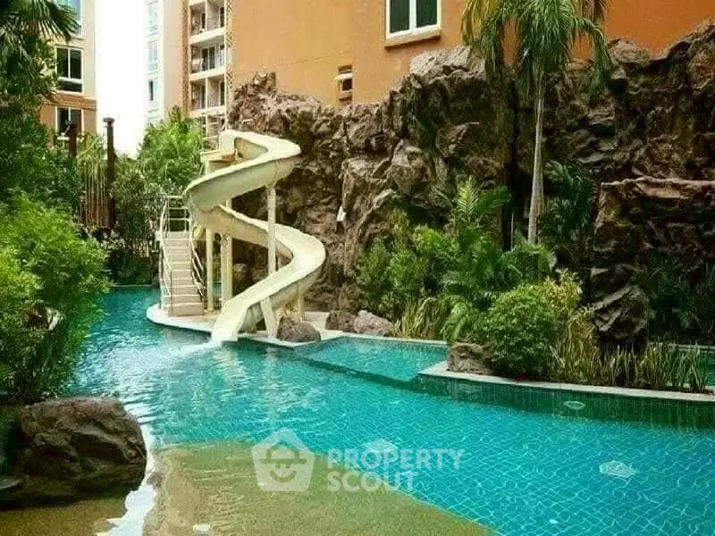 Luxurious outdoor pool with water slide and lush greenery in a modern residential complex.