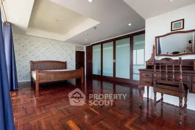 Spacious bedroom with wooden flooring and elegant furniture in a modern apartment.