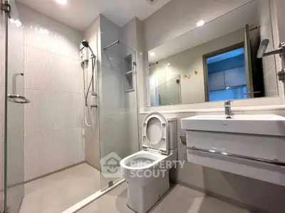 Modern bathroom with glass shower and sleek fixtures in contemporary apartment.