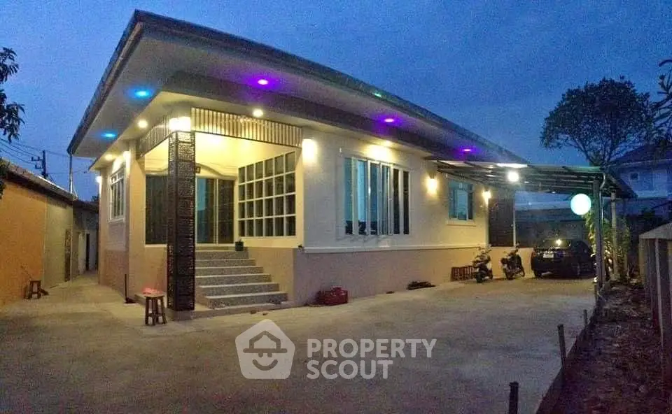 Modern single-story house with colorful exterior lighting and spacious driveway.