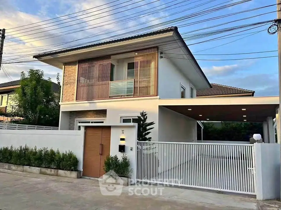 Modern two-story house with sleek design and gated entrance in a suburban neighborhood.
