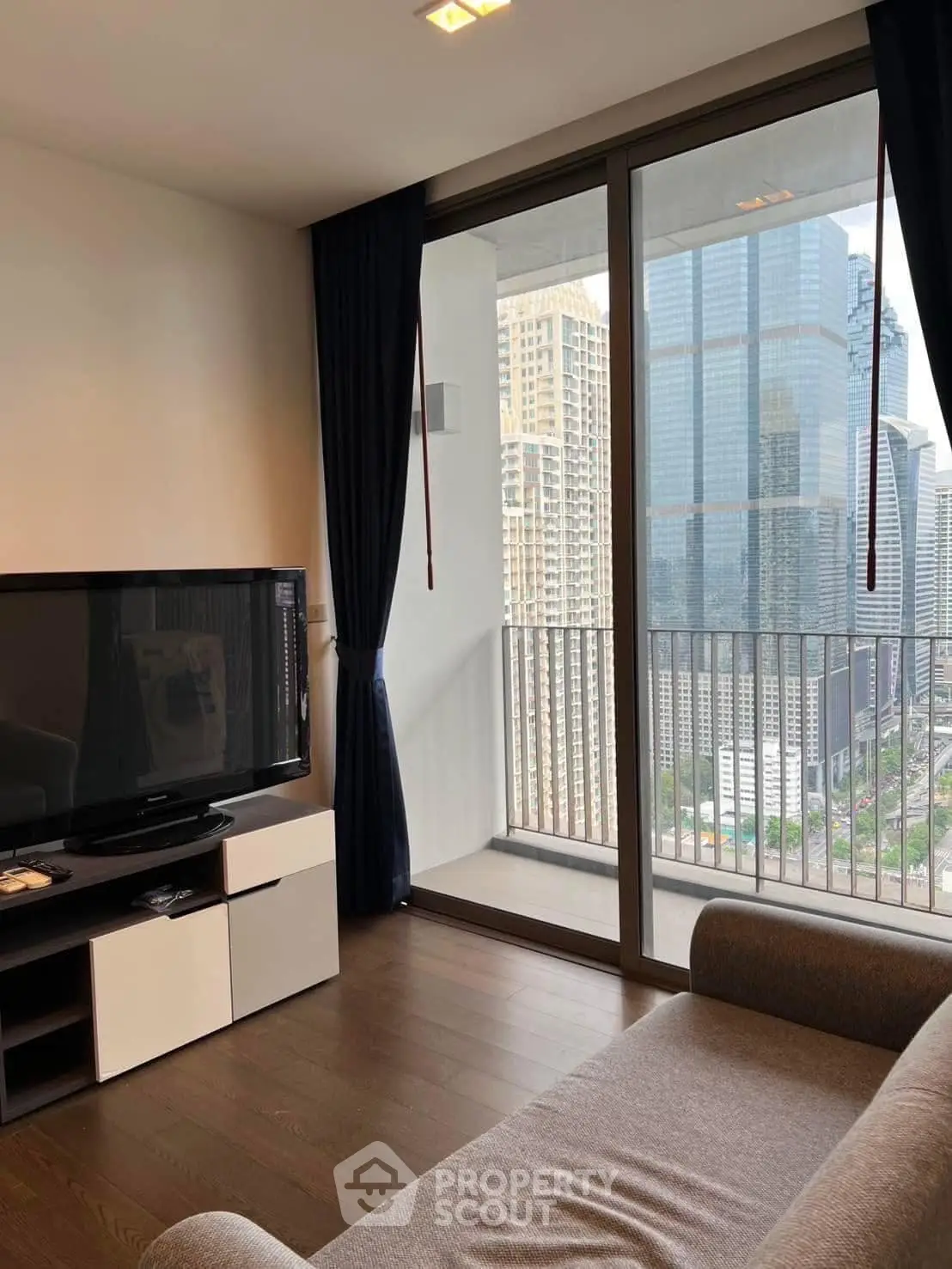 Modern living room with city view and large glass doors leading to a balcony.