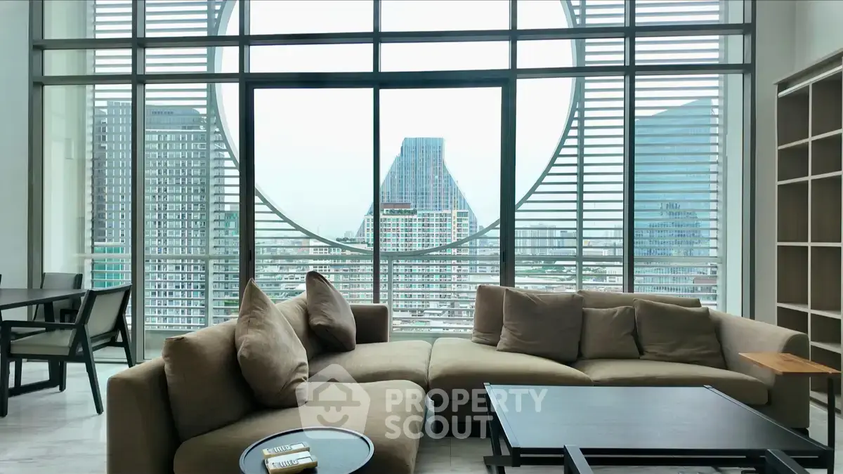 Spacious living room with modern furniture and stunning city view through large windows.