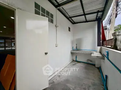 Spacious outdoor utility area with sink and covered roof, ideal for laundry or storage.