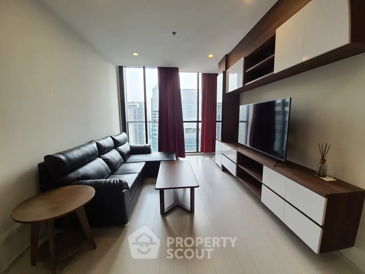 Modern living room with sleek furniture and city view, featuring a large TV and stylish shelving.