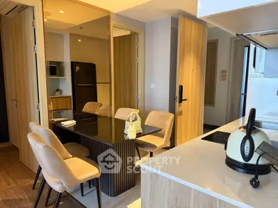 Modern kitchen with dining area featuring sleek black table and beige chairs, adjacent to a compact fridge.