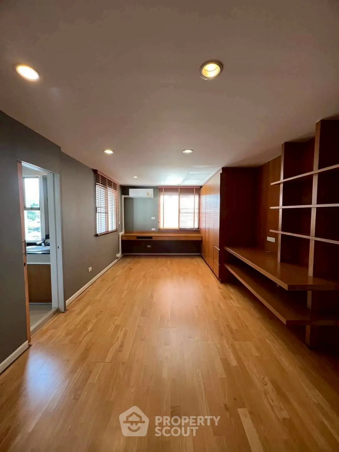 Spacious room with wooden flooring and built-in shelves, ideal for versatile use.