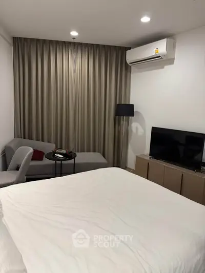 Cozy bedroom with modern decor, featuring a comfortable bed, stylish chaise lounge, and wall-mounted TV.