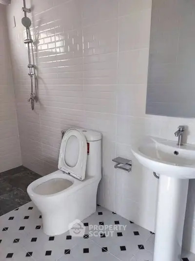 Modern bathroom with white tiles, toilet, and pedestal sink