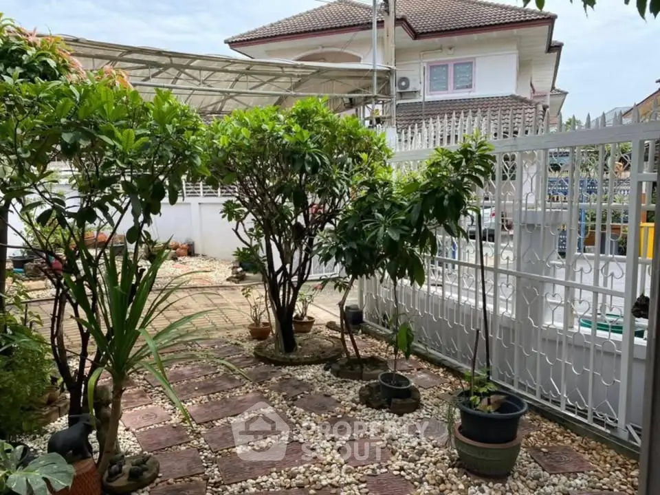 Charming garden with lush greenery and stone pathway in a serene residential setting.