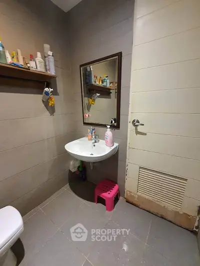 Cozy bathroom with modern sink and mirror, featuring ample storage and neutral tiles.