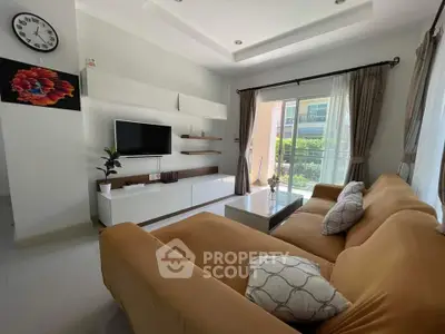Modern living room with cozy sofa and sleek entertainment unit, featuring large windows for natural light.