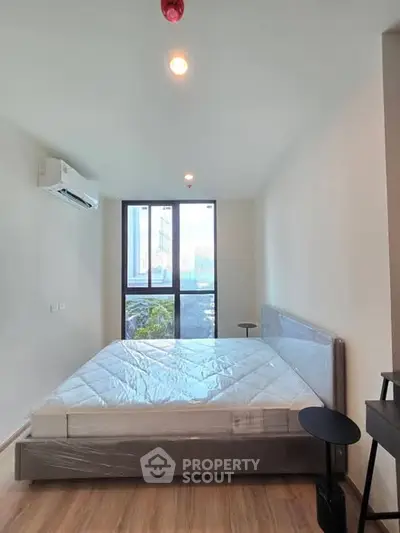 Modern bedroom with large window and air conditioning in a stylish apartment.