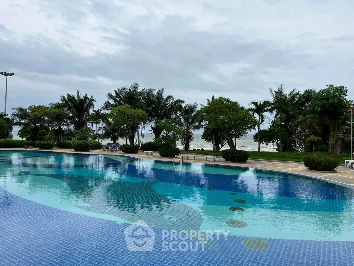 Luxurious poolside view with lush greenery and ocean backdrop, perfect for relaxation and leisure.