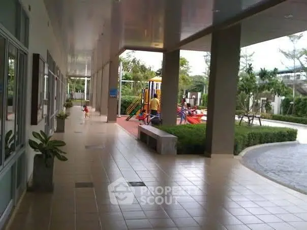 Spacious outdoor area with playground and covered walkway in modern residential complex.