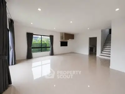 Spacious modern living room with large windows and elegant staircase