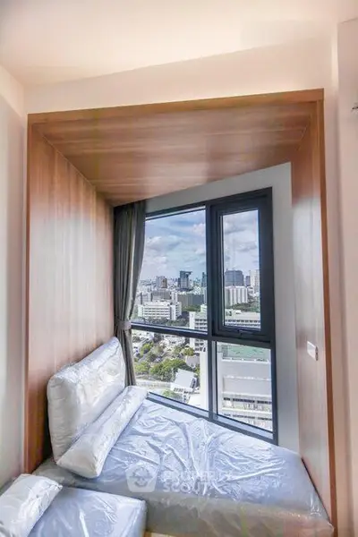 Modern bedroom with stunning city view through large windows in a high-rise apartment.