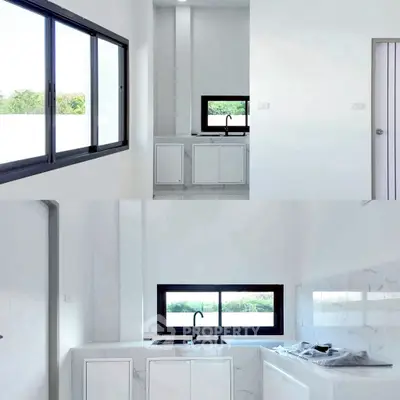 Modern kitchen with sleek white cabinetry and large windows offering natural light.