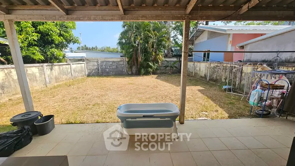 Spacious backyard with covered patio and lush greenery, perfect for outdoor activities and relaxation.