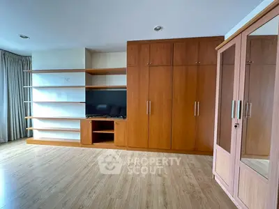 Spacious bedroom with built-in wooden wardrobe and modern shelving unit.