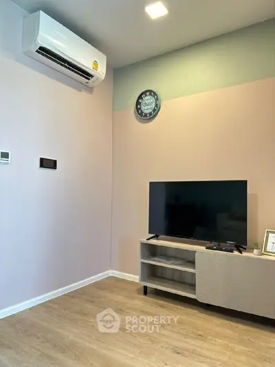 Modern living room with air conditioning and flat-screen TV on wooden floor