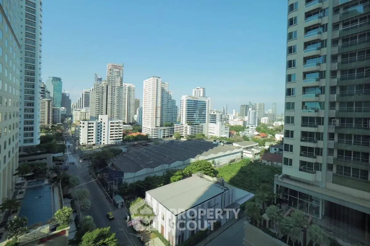 Stunning cityscape view from high-rise apartment with modern buildings and lush greenery.