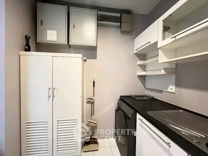 Modern laundry room with sleek cabinetry and washing machine in a stylish home.