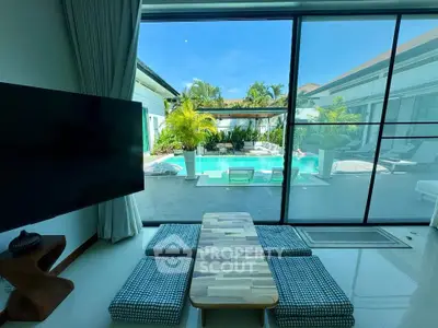 Luxurious living room with pool view in modern villa, featuring sleek design and tropical landscaping.