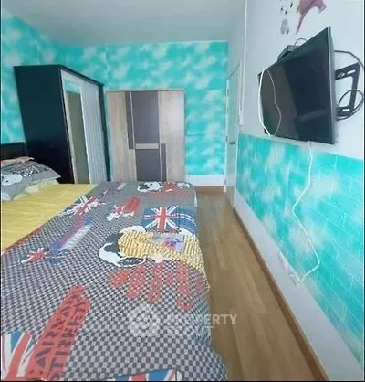 Vibrant bedroom with colorful bedding and wall-mounted TV, featuring modern wardrobe and wooden flooring.