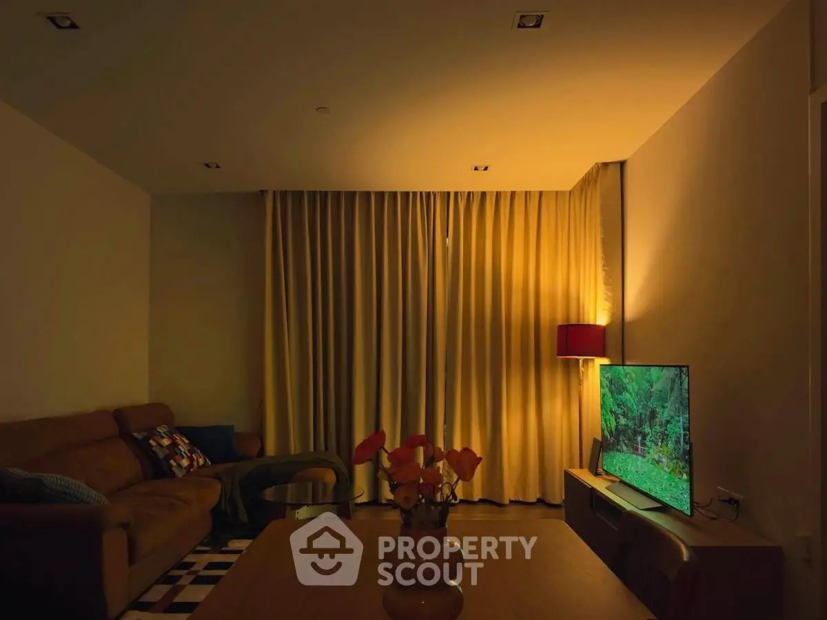 Cozy living room with warm lighting, modern sofa, and flat-screen TV for ultimate relaxation.