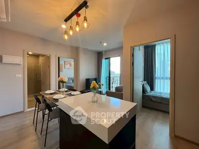 Modern open-plan living area with stylish lighting and cozy bedroom view