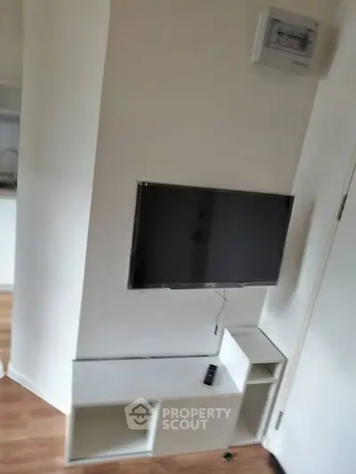 Modern living room with mounted TV and sleek storage unit in a stylish apartment.