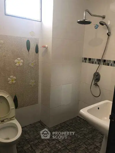 Compact bathroom with shower, toilet, and sink featuring floral tile accents.