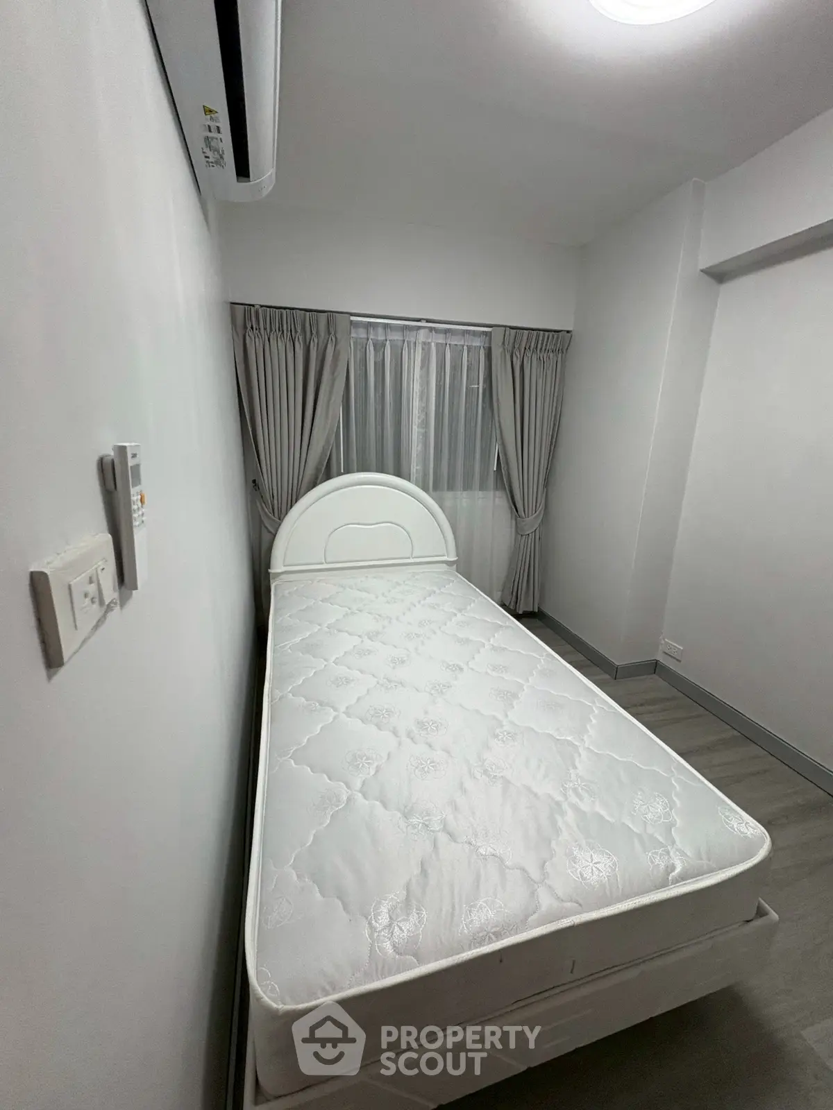 Cozy minimalist bedroom with single bed and elegant curtains, perfect for a peaceful retreat.