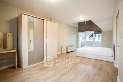 Spacious bedroom with modern furniture and large window offering natural light.