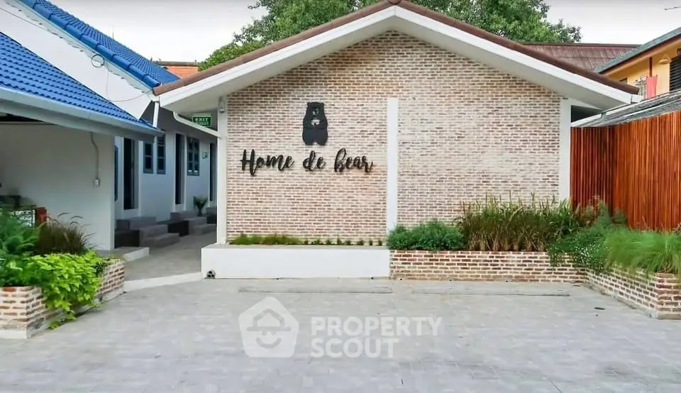 Charming brick exterior with lush greenery at Home de Bear property entrance.