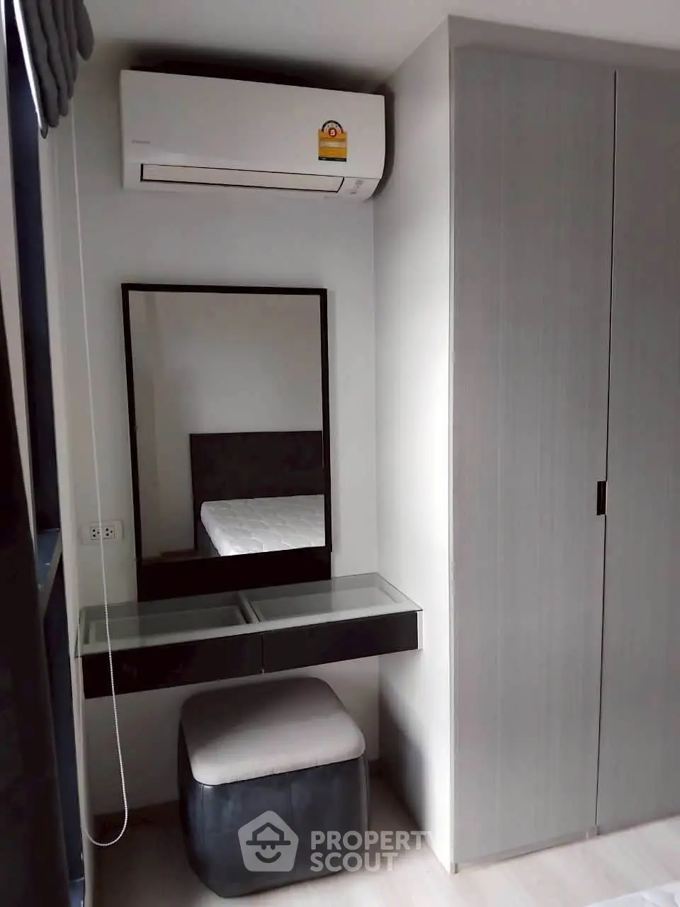 Modern bedroom with sleek wardrobe and air conditioning unit, featuring a stylish vanity area.