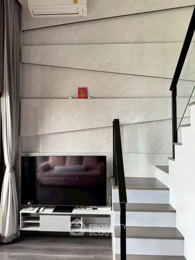 Modern living room with sleek TV setup and stylish staircase