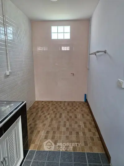 Compact utility room with tiled flooring and natural light, ideal for laundry or storage.