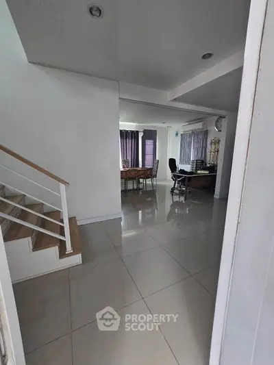 Spacious open-plan living area with modern staircase and tiled flooring