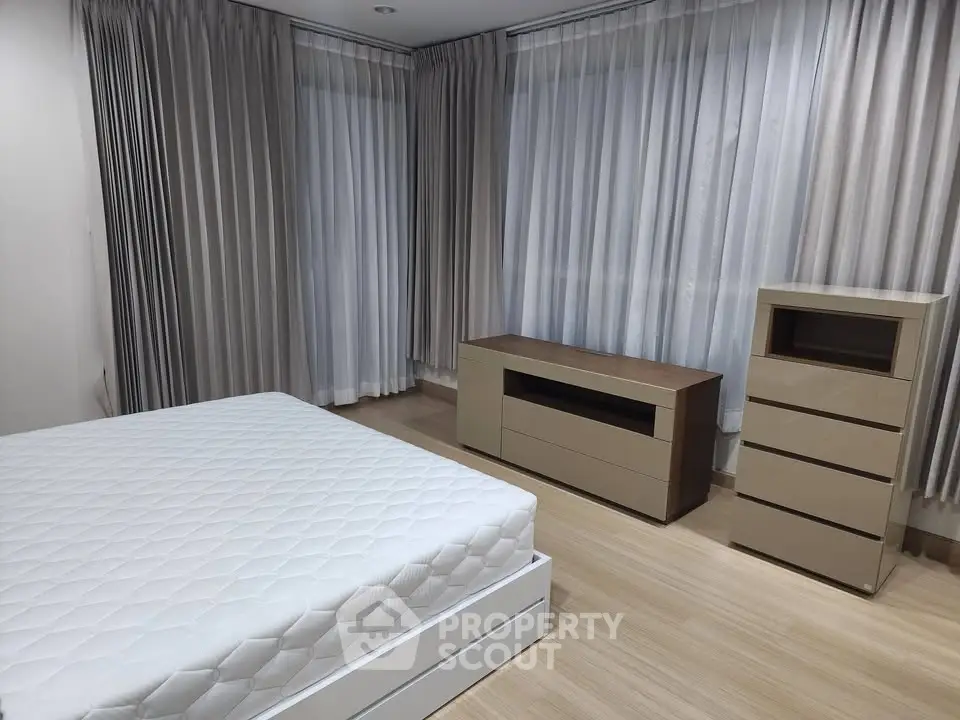 Spacious bedroom with modern furniture and elegant curtains, perfect for a serene living experience.