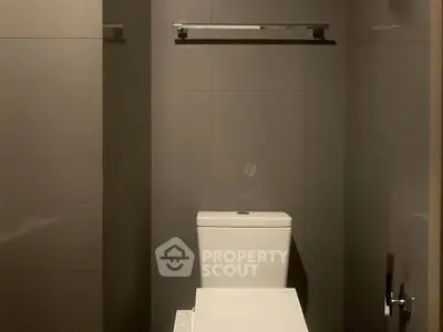 Modern minimalist bathroom with sleek gray tiles and contemporary toilet design.