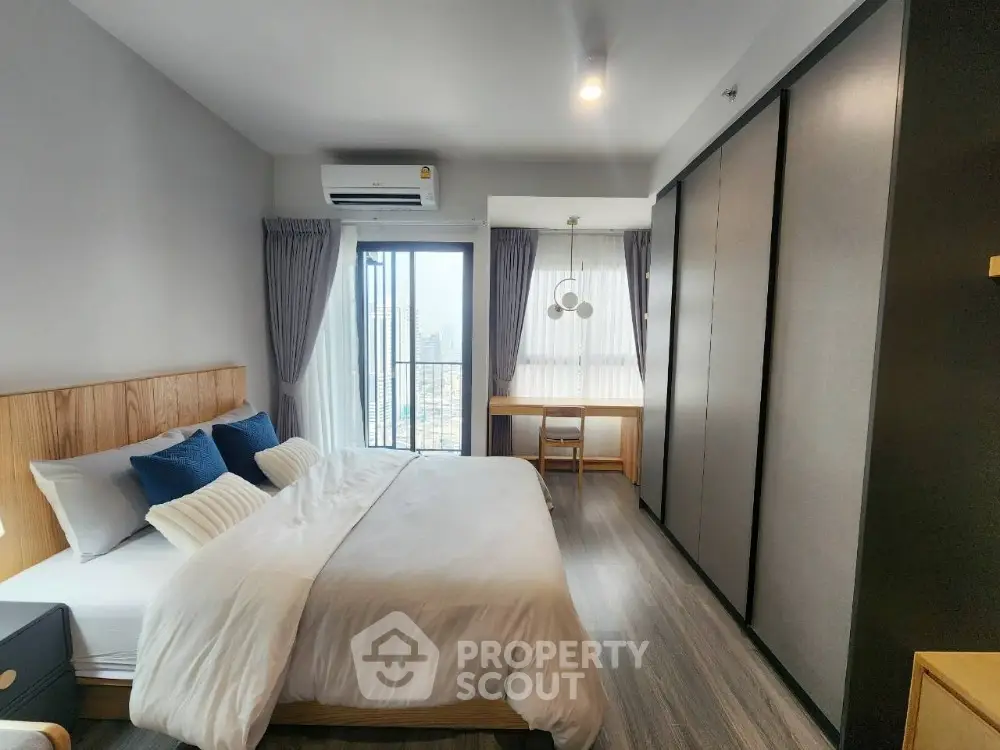 Modern bedroom with city view, featuring sleek design and ample natural light.