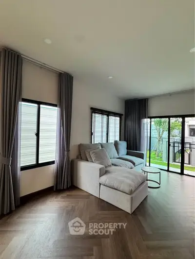 Spacious living room with modern decor and large windows overlooking garden