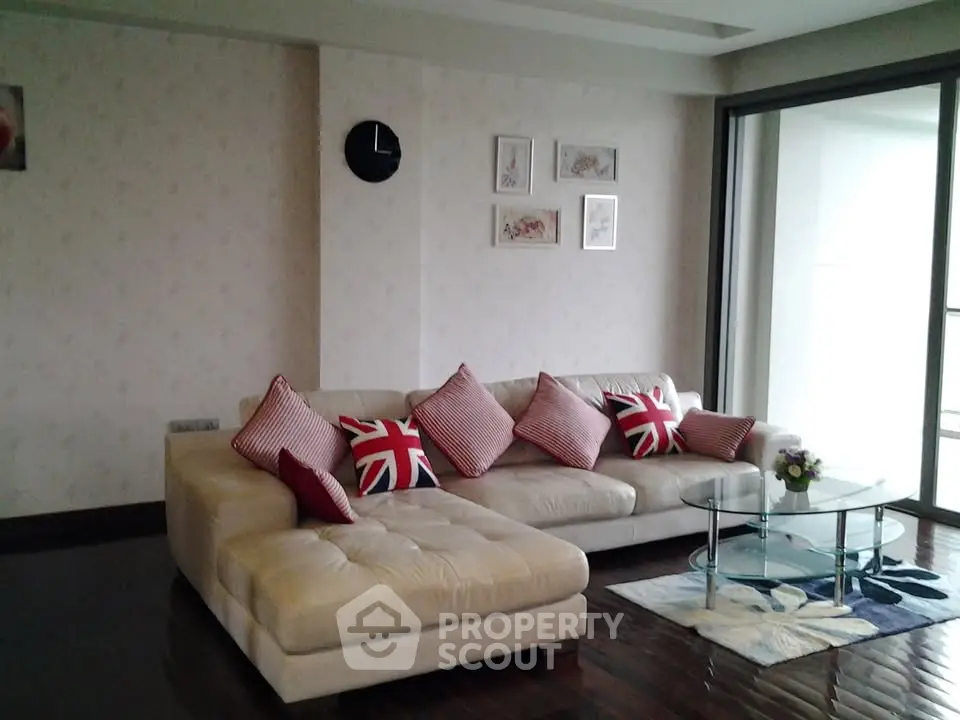 Stylish living room with modern sectional sofa and glass coffee table, featuring elegant decor and natural light.