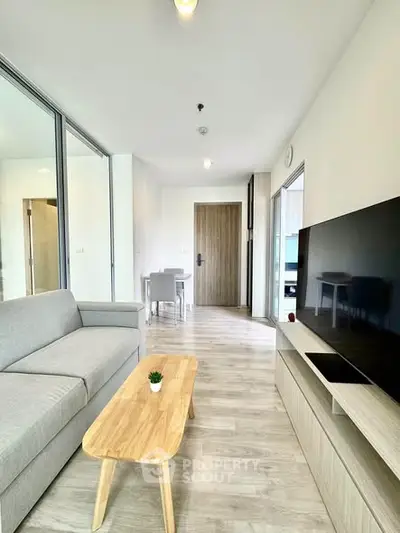 Modern living room with sleek furniture and large TV in a bright apartment.